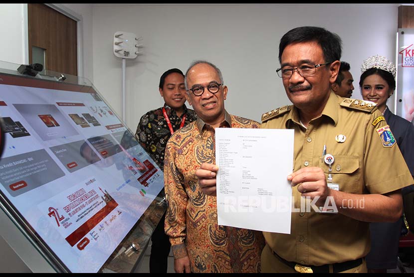 Gubernur DKI Jakarta Djarot Saiful Hidayat (kanan) melakukan transaksi pembayaran s