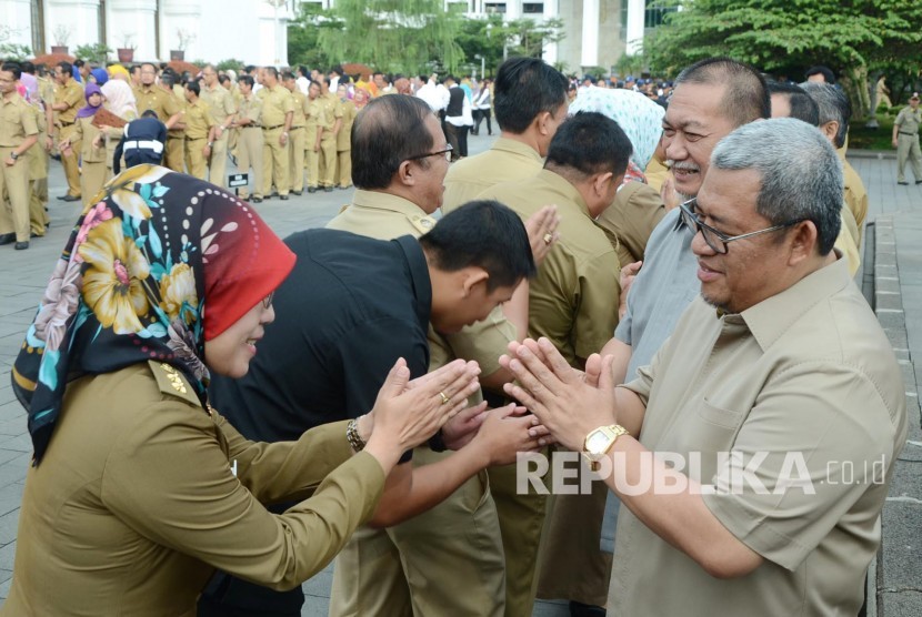 Gubernur Jabar Ahmad Heryawan, dan Wakil Gubernur Jabar Deddy Mizwar bersalaman dengan para Pegawai Negeri Sipil (PNS) pada upacara pagi hari pertama masuk kerja usai libur Lebaran, di Halaman Gedung Sate, Kota Bandung, Senin (11/7). (Republika/Edi Yusuf)