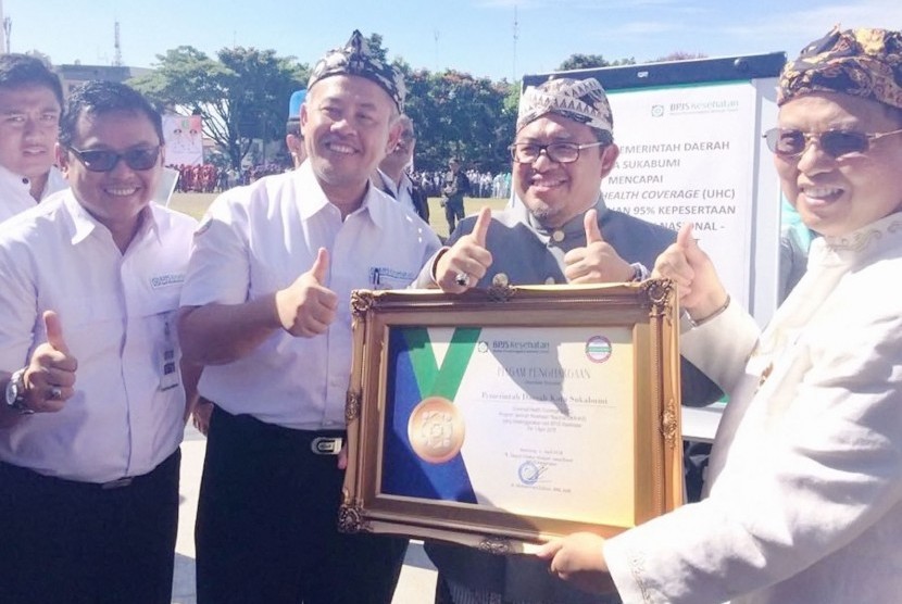 Gubernur Jabar Ahmad Heryawan (tengah), Wali Kota Sukabumi (kanan), dan Deputi Direksi BPJS Kesehatan Kedeputian Wilayah Jawa Barat Mohammad Edison (ketiga dari kanan) menunjukkan piagam deklarasi penetapan Universal Health Coverage (UHC) dalam peringatan Hari Jadi Kota Sukabumi ke-104 di Lapang Merdeka, Kota Sukabumi(1/04).      