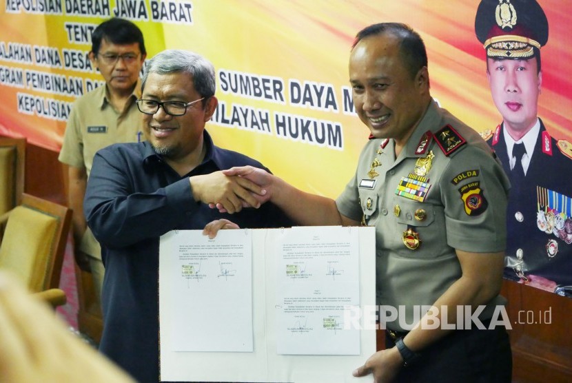 Gubernur Jabar Ahmad Heryawan dan Kapolda Jabar Irjen Pol Agung Budi Maryoto memegang lembar kesepakan kerjasama Penanganan Permasalahan Dana Desa dan Peningkatan Sumber Daya Manusia Melalui Program Pembinaan dan Pelatihan di Wilayah Hukum Kepolisian Daerah Jabar, di Gedung Sate, Kota Bandung, Senin (30/10).