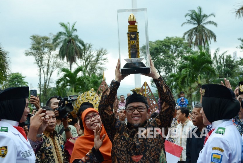 Gubernur Jawa Barat Ahmad Heryawan didampingi istri mengangkat penghargaan Parasamya Purnakarya Nugraha dari Presiden Republik Indonesia atas prestasi kinerja tertinggi secara nasional, di depan Gedung Sate, Kota Bandung, Kamis (26/4).