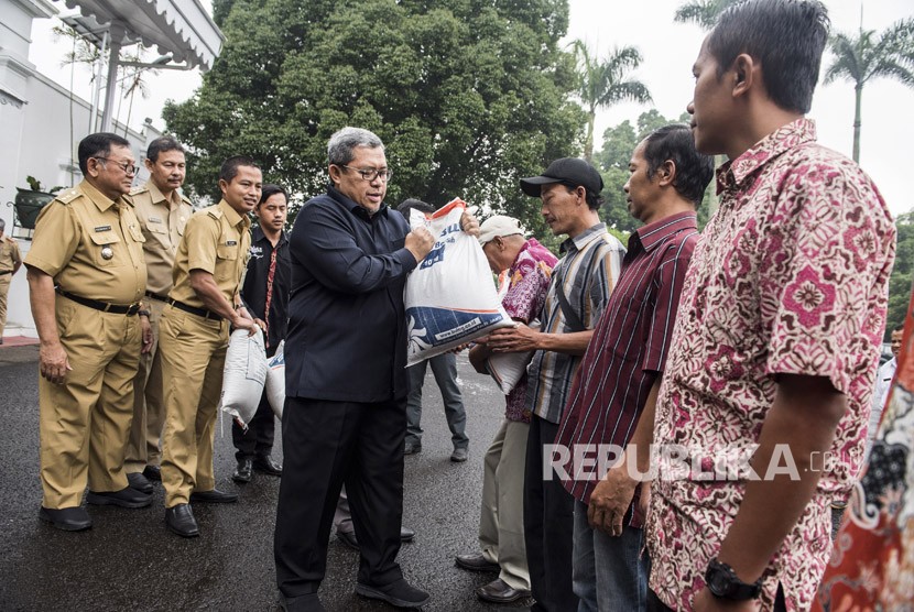 Gubernur Jawa Barat Ahmad Heryawan memberikan bantuan sosial (bansos) beras sejahtera (rastra) kepada warga di gedung Pakuan, Bandung, Jawa Barat, Senin (5/3). 