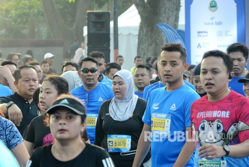 Gubernur Jawa Barat Ridwan Kamil (berkecamata) beserta peserta lain memasuki garis finis pada ajang Bandung West Java Marathon 2019, di depan Gedung Sate, Jalan Diponegoro, Kota Bandung, Ahad (28/7).