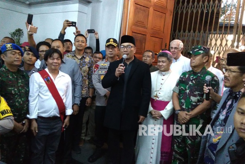 Gubernur Jabar Ridwan Kamil (berpeci) didampingi Kapolda Jabar Irjen Agung Budi Maryoto dan Wakil Wali Kota Bandung Yana Mulyana, menyampakan sambutaan saat meninjau pelaksanaan misa malam Natal 2018, di Gereja Katedral Santo Petrus Bandung, Senin (24/12). 