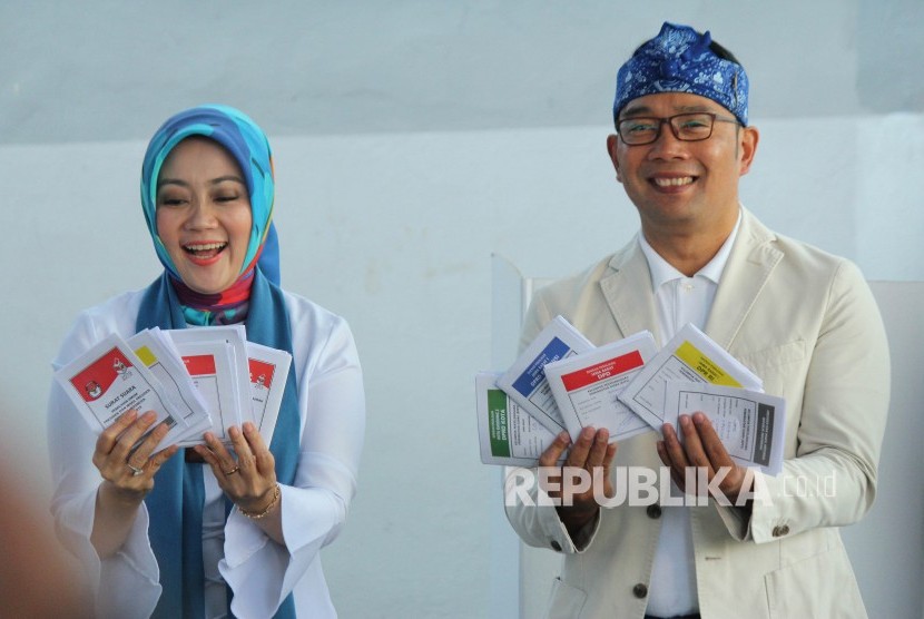 Gubernur Jawa Barat Ridwan Kamil berserta istrinya Atalia Praratya memperlihatkan surat suara usai melakukan pencoblosan Pemilu 2019, di TPS 32, Cigadung, Kota Bandung, Rabu (17/4).