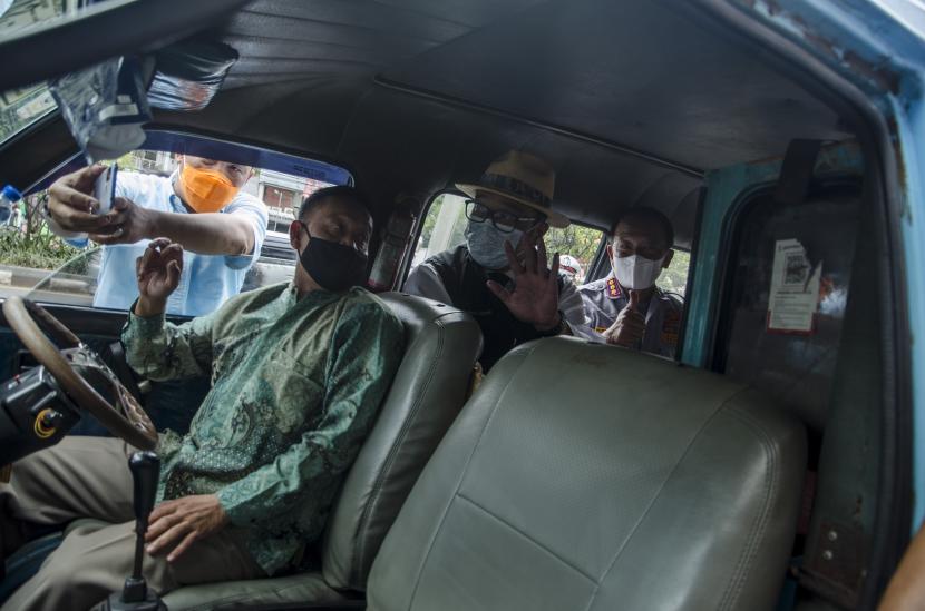 Gubernur Jawa Barat Ridwan Kamil (kedua kanan) memberikan informasi kepada sopir angkutan kota saat uji coba digitalisasi angkutan umum di Halte Djundjunan, Bandung, Jawa Barat, Jumat (7/1/2022). Tarif angkutan kota Bandung resmi naik Rp 1.000 mulai hari ini, Senin (12/9/2022).