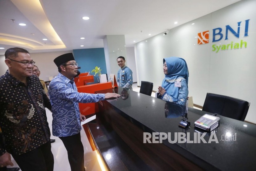 Gubernur Jabar Ridwan Kamil (kedua kiri) dan Direktur Utama PT Bank BNI Syariah Abdullah Firman Wibowo (kiri) meninjau pelayanan usai meresmikan Relokasi BNi Syariah Kantor Wilayah dan Cabang Bandung, di Jalan Asia Afrika, Kota Bandung, Selasa (13/11).