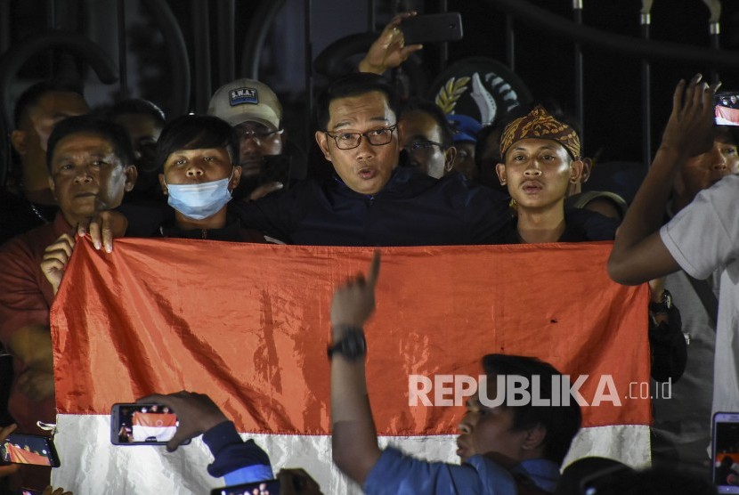 Gubernur Jawa Barat Ridwan Kamil (tengah) bersama perwakilan pelajar dan mahasiswa memegang bendera merah putih disela aksi unjuk rasa di depan Gedung Sate, Kota Bandung, Sabtu (28/9) malam.