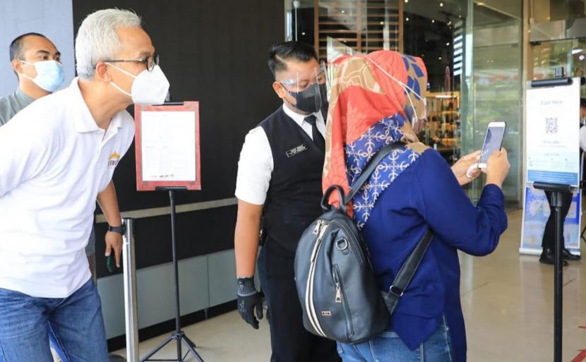 Gubernur Jawa Tengah, Ganjar Pranowo melihat proses pengecekan bukti telah mendapatkan vaksinasi Covid-19, kepada pengunjung Mal Paragon, Kota Semarang, Rabu (11/8). Mal ini telah dua hari melakukan uji coba pembkaan dengan mensyaratkan pengunjung harus sudah divaksin Covid-19.