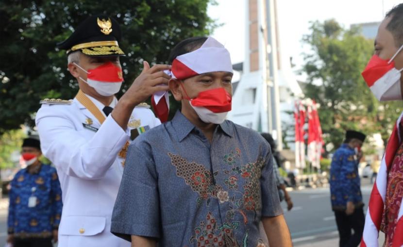 Gubernur Jawa Tengah, Ganjar Pranowo, mengikatkan hasduk merah putih pada kepala eks napiter yang diundang untuk mengikuti upacara puncak peringatan HUT Kemerdekaan RI ke-77, di lapangan Pancasila, Simpanglima, ota Semarang, Rabu (17/8).