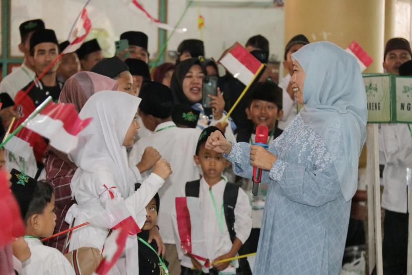 Gubernur Jawa Timur Khofifah Indar Parawansa bersama anak-anak mengibarkan bendera merah putih.