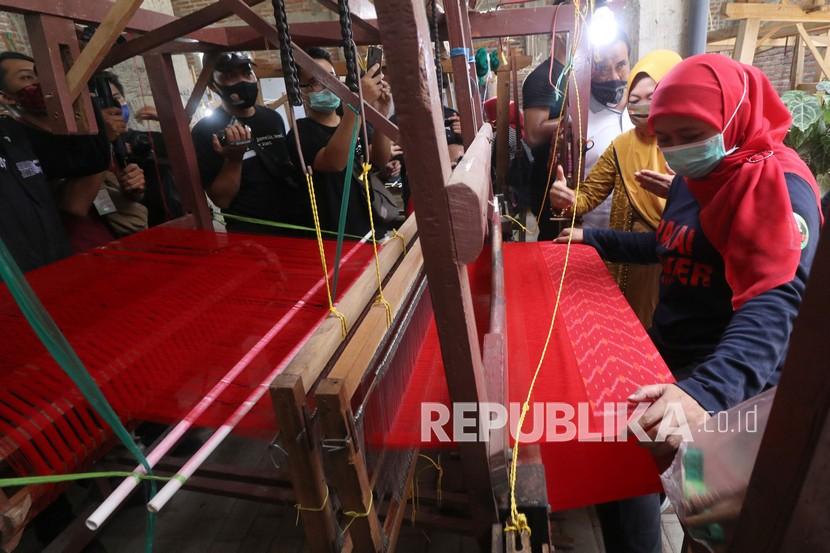 Gubernur Jawa Timur Khofifah Indar Parawansa (kanan) mencoba mengoperasikan alat tenun bukan mesin milik pelaku umkm..