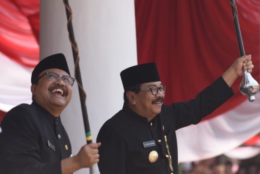 Gubernur Jawa Timur Soekarwo (kanan) dan Wakil Gubernur Jawa Timur Saifullah Yusuf (kiri) memainkan tongkat mayoret drum band pada Upacara Peringatan HUT ke-70 Jawa Timur di Grahadi, Surabaya, Jawa Timur, Senin (12/10). 