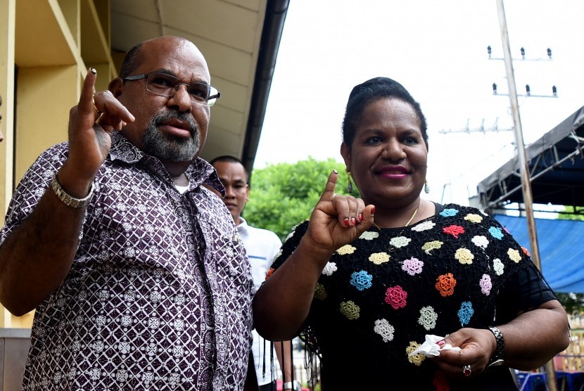 Gubernur Provinsi Papua, Lukas Enembe bersama istri Yulce Enembe menunjukkan jari sebagai tanda telah mencoblos di TPS 23 Jayapura Selatan, Rabu (15/2).
