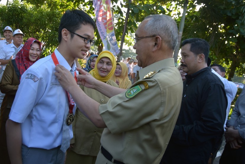 Gubernur Riau Arsyadjuliandi Rachman mengalungkan medali saat menyambut peraih medali emas Olimpiade Kimia Internasional Dean Fanggohans di SMAN 8, Kota Pekanbaru, Senin (17/7).