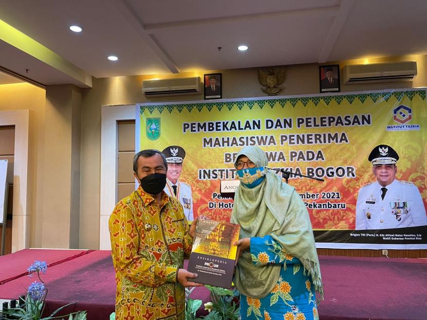 Gubernur Riau Syamsuar dan Rektor Institut Tazkia Murniati Mukhlisin, bertukar cendramata.