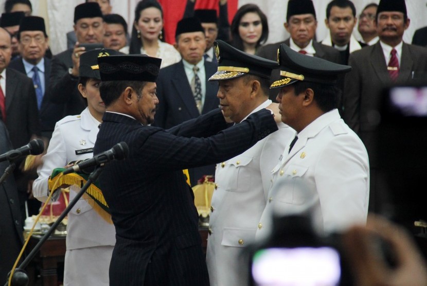 Gubernur Sulawesi Selatan Syahrul Yasin Limpo (kiri) menyematkan tanda jabatan kepada Bupati Toraja Utara Kalatiku Paembonan (tengah) dan Wakil Bupati Yosia Rinto Kadang (kanan) saat pelantikan Bupati dan Wakil Bupati Toraja Utara di kantor Gubernur Sulsel