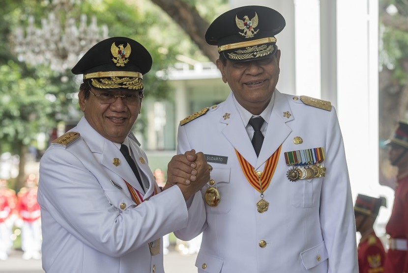 Gubernur Sulawesi Tengah terpilih Longki Djanggola (kiri) berjabat tangan dengan Wakil Gubernur Sulawesi Tengah terpilih Sudarto (kanan) sebelum menerima petikan Keppres di Istana Merdeka, Jakarta, Kamis (16/6). 