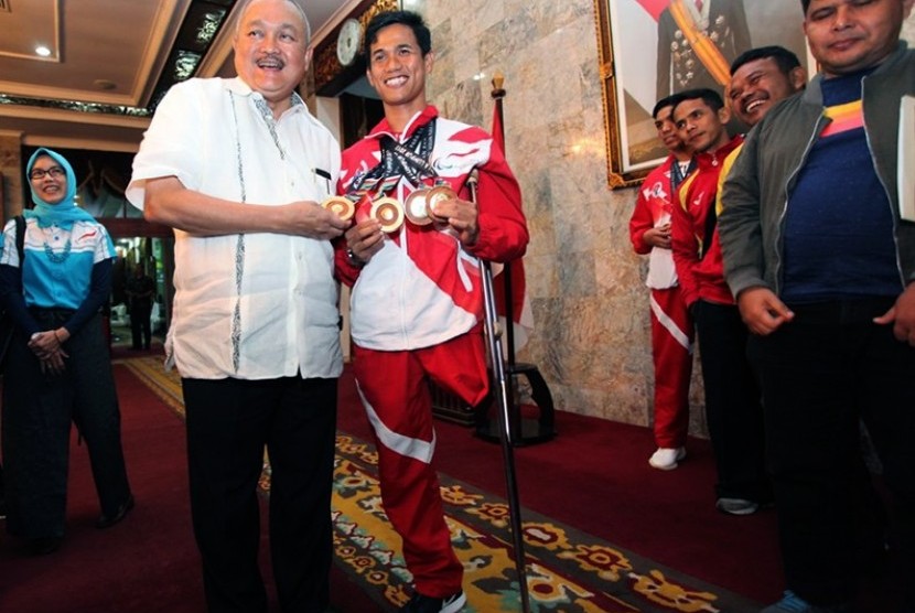 Gubernur Sumatera Selatan, Alex Noerdin, bersama atlet Asean Paragames, Jendi Panggabean, yang meraih lima medali emas dari cabang renang. 