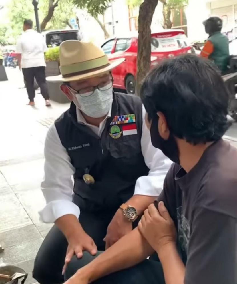 Gunernur Jawa Barat Ridwan Kamil berbincang dengan seorang pelukis jalanan di Jalan Braga, yang lukisannya dijual lewat platform NFT. 