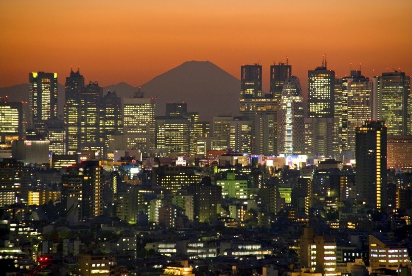 Gunung Fuji menjadi latar pemandangan saat senja di tengah belantara gedung pencakar langit Shinjuku di Tokyo, Jepang.
