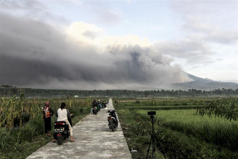  Gunung Semeru memuntahkan material vulkanik ke udara saat orang-orang menyaksikan erupsi di Lumajang, Jawa Timur, Ahad, 4 Desember 2022. Pusat Vulkanologi dan Mitigasi Bencana Geologi (PVMBG) memaparkan alasan meningkatkan status Gunung Semeru di Jawa Timur menjadi Level IV atau Awas.