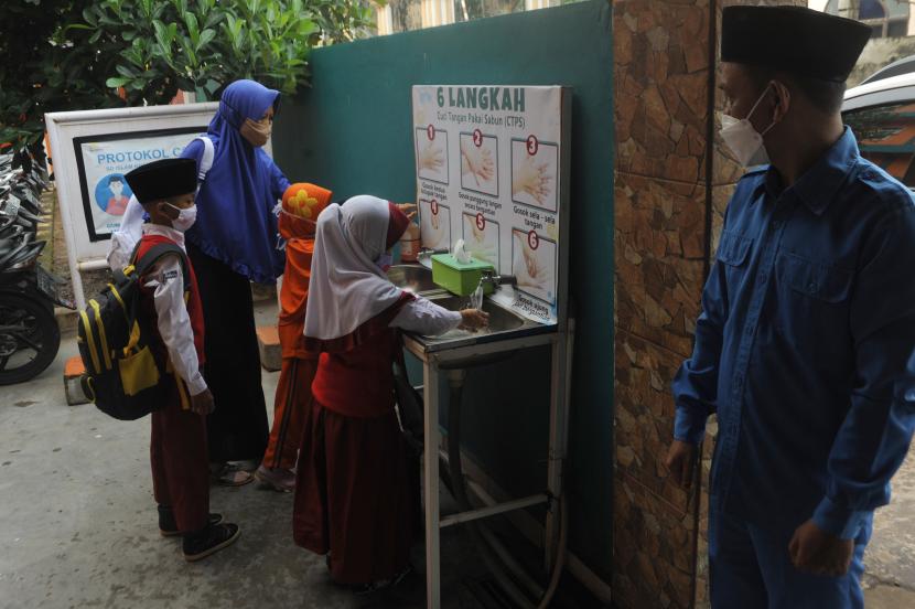 Guru membantu para siswa mencuci tangan sebelum masuk ke ruang kelas di Sekolah Islam Khalifah Annizam Palembang, Sumatra Selatan, Senin (6/9/2021). Pembelajaran Tatap Muka (PTM) di sekolah tahap pertama di Kota Palembang dilaksanakan oleh 120 sekolah yang telah diverifikasi Dinas Pendidikan setempat.