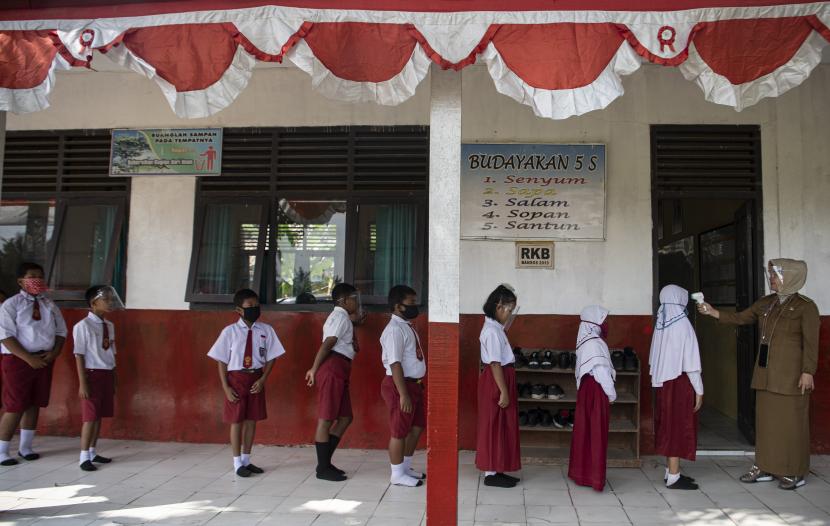 Guru memeriksa suhu tubuh siswanya sebelum mengikuti Kegiatan Belajar Mengajar (KBM) tatap muka di SD Negeri 26 Sukajadi, Banyuasin, Sumatra Selatan, Senin (7/9/2020). 
