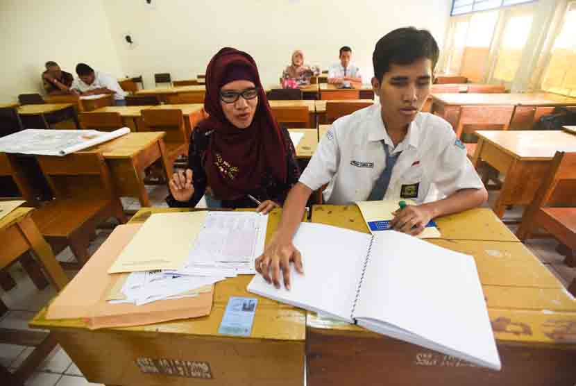 Guru mendampingi siswa berkebutuhan khusus mengikuti ujian nasional paper based test (Pbt) di SMAN 10 Surabaya, Jawa Timur, Senin (13/4). ANTARA/Zabur Karur