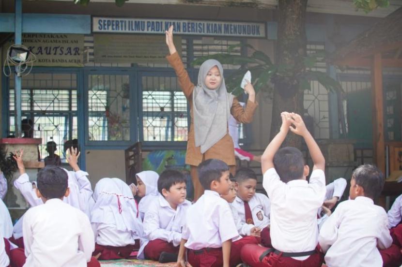 Guru SDN 16 Banda Aceh sedang mengajar peserta didik di luar ruangan sebagai upaya menghadapi suhu panas, di Banda Aceh, Selasa (7/5/2024). 