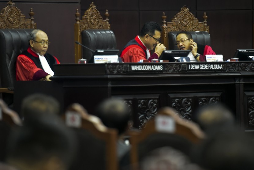 Hakim konstitusi Suhartoyo (kanan) berbincang dengan Hakim Konstitusi I Dewa Gede Palaguna (tengah), Hakim Konstitusi Wahiduddin Adams (kiri) saat memimpin sidang putusan gugatan quick count atau hitung cepat pada Pemilu serentak 2019 di Mahkamah Konstitusi, Jakarta, Selasa (16/4/2019). 