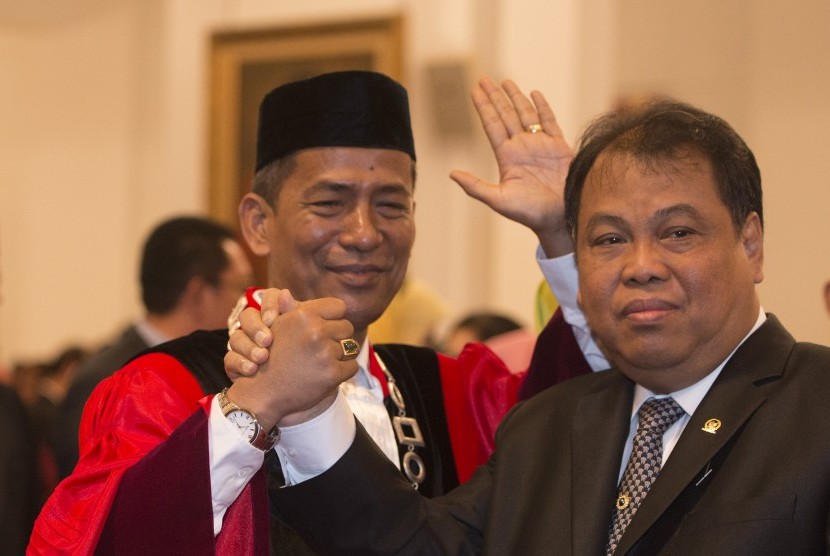 Hakim Mahkamah Konstitusi (MK) yang baru Saldi Isra (kiri) berjabat tangan dengan Ketua MK Arief Hidayat usai pelantikan hakim MK di Istana Negara, Jakarta, Selasa (11/4). 
