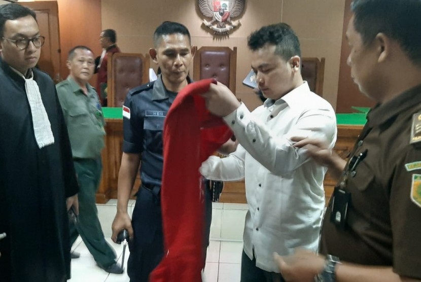 Haris Simamora sedang memasang kembali rompinya untuk keluar dari ruang sidang Pengadilan Negeri Bekasi, Selasa (31/7). Terdakwa kasus pembunuhan satu keluarga ini dijatuhi hukuman pidana mati oleh majelis hakim.