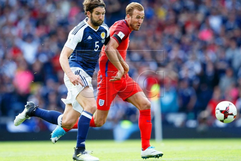 Harry Kane (kanan) dari Inggris berebut bola dengan pemain Skotlandia Charlie Mulgrew dalam laga kualifikasi Piala Dunia 2018 zona Eropa di Hampden Park, Glasgow, Sabtu (10/6) waktu setempat. Pertandingan itu berakhir 2-2. 