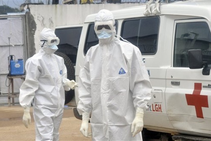 Health workers wearing protective gear wait to carry the body of a person suspected to have died from Ebola, in Monrovia, Liberia, Monday Oct. 13, 2014. 