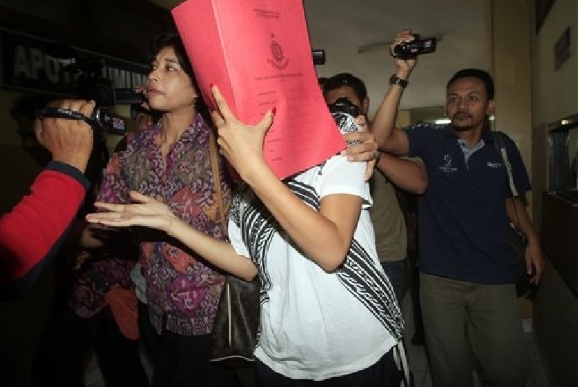 Heather Mack, covering her face, is led to a hospital for a medical check by Indonesian police officers in relation to the death of her mother Sheila von Wiese-Mack in Bali, Indonesia, Friday, Aug. 15, 2014.