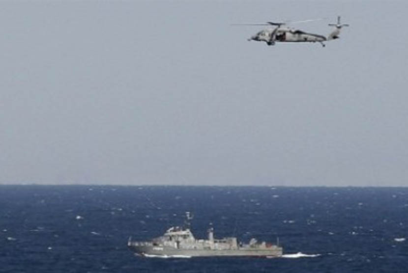 Helikopter angkatan laut AS terbang rendah di atas kapal perusak, Sterett, saat melintasi Selat Hormuz
