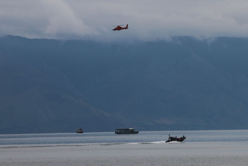 Helikopter Basarnas jenis Dauphin HR-3604 terbang di atas Danau Toba saat melaksanakan pencarian korban tenggelamnya KM Sinar Bangun, di Simalungun, Sumatera Utara, Sabtu (23/6). 