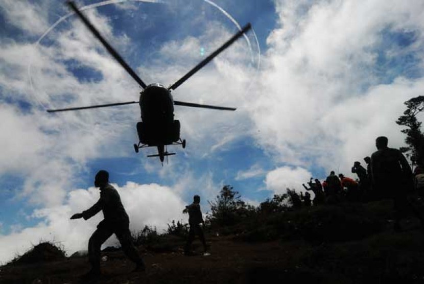 Helikopter dibantu petugas TNI dan sejumlah relawan bersiap mengevakuasi korban jatuhnya pesawat Sukhoi Superjet 100 di Puncak I Gunung Salak, Kabupaten Bogor, Jawa Barat, Ahad (13/5)