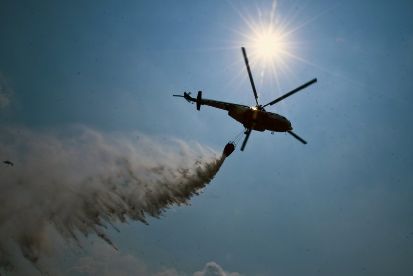 Helikopter MI 17 dari Badan Nasional Penanggulangan Bencana (BNPB) menjatuhkan bom air di atas lahan yang terbakar di Kecamatan Payung Sekaki, Kota Pekanbaru, Riau, Jumat (24/7).