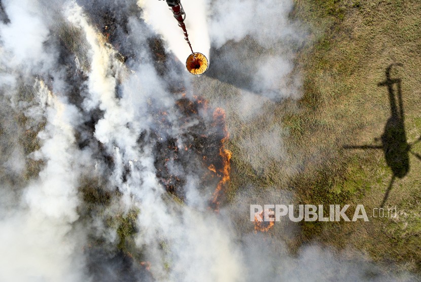 Helikopter MI-172 milik Badan Nasional Penanggulangan Bencana (BNPB) melakukan pemadaman kebakaran lahan dari udara water boombing di Tulung Selapan, Ogan Komering Ilir (OKI), Sumatera Selatan, Ahad (22/7). 