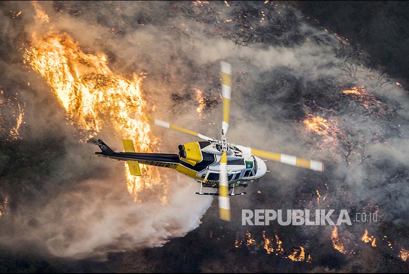 Helikopter pemadam kebakaran melintasi  api liar yang menyapu  Distrik Bel Air, Kalifornia, Amerika Serikat.