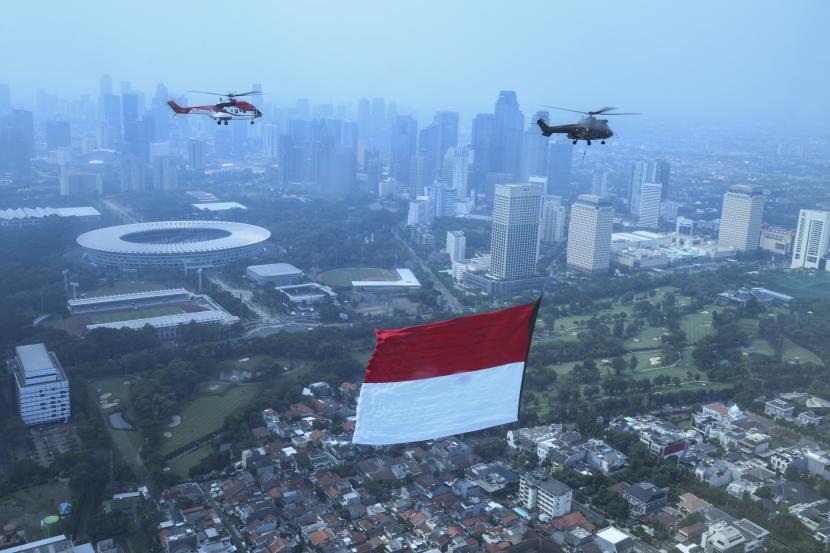 Helikopter TNI AU mengibarkan bendera merah putih raksasa di kawasan Wisma Atlet, Jakarta.