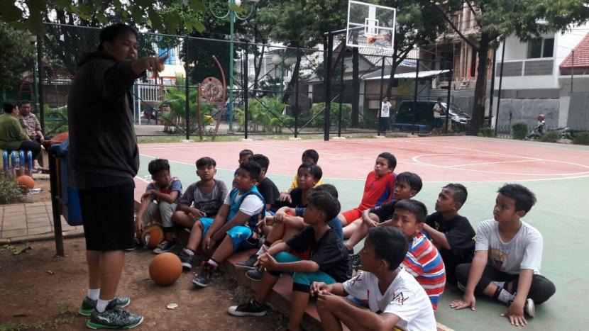 Hendi Aries Pratama (kiri) saat melatih anak-anak bermain basket.