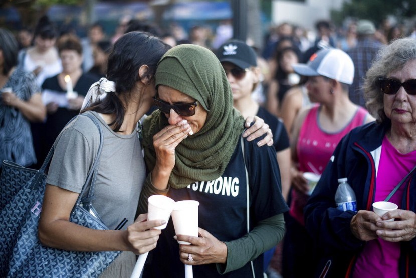 Hina Moheyuddin (kiri) menenangkan Noshaba Afzal saat acara mengenang korban penembakan di festival bawang putih Gilroy Garlic Festival, Senin (29/7) di Gilroy, Kalifornia.