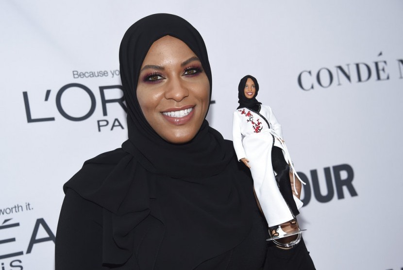 Ibtihaj Muhammad memegang boneka Barbie berhijab yang terinspirasi darinya.