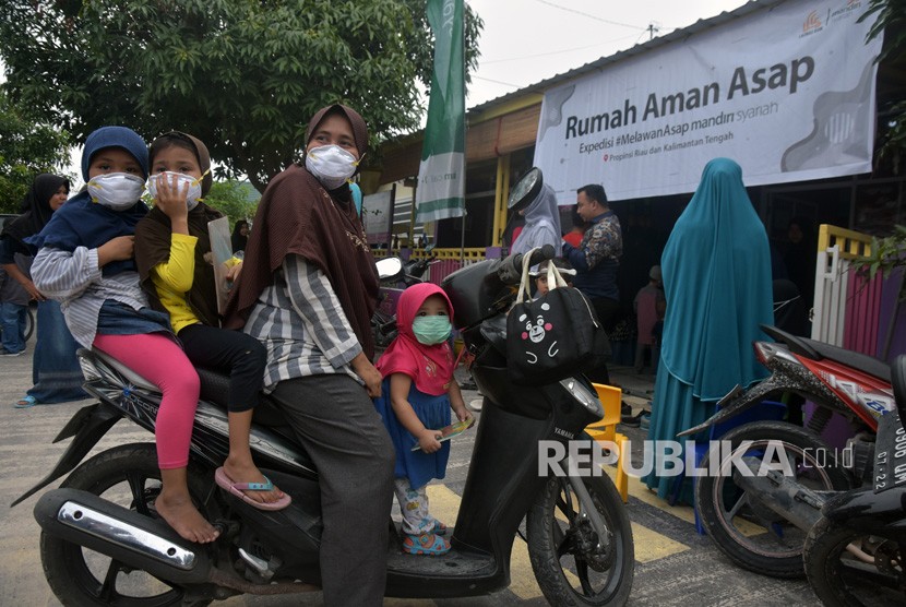Ibu dan anak-anaknya mengenakan masker saat mengunjungi Rumah Aman Asap di Kota Pekanbaru, Riau, Rabu (25/9/2019). 