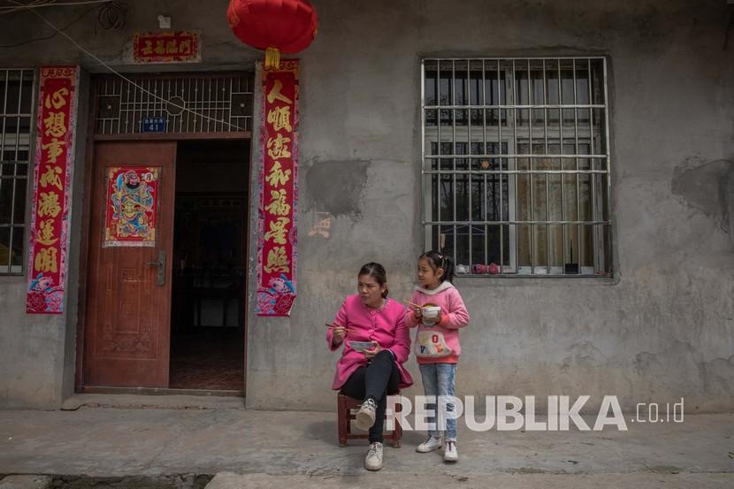  Ibu dan anak makan di depan rumah mereka di wilayah pedesaan Wuhan, Cina, Selasa (14/4). Sebagian besar penduduk desa di daerah pedesaan Wuhan kembali bekerja di ladang setelah dicabutnya lockdown . Wuhan yang merupakan pusat penyebaran wabah koronavirus, telah mencabut lockdown pada 08 April 2020. 