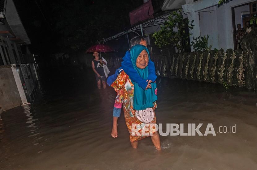 Ibu membawa anaknya mengungsi dari banjir di Rangkasbitung, Lebak, Banten, Rabu (12/1/2022). Hingga Rabu (12/1/2022) malam hari, hujan masih mengguyur daerah tersebut sehingga warga terpaksa mengungsi ke tempat yang lebih aman akibat debit air terus meninggi. 
