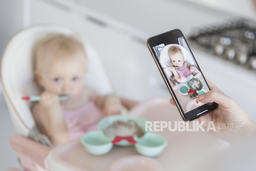 Ibu mengambil foto anaknya (ilustrasi). Orang tua diimbau tidak sembarangan membagikan foto anak mereka di media sosial ataupun platform Al. 